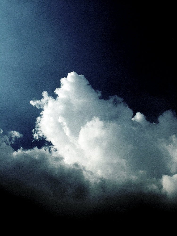 a jet flying through the clouds on a sunny day