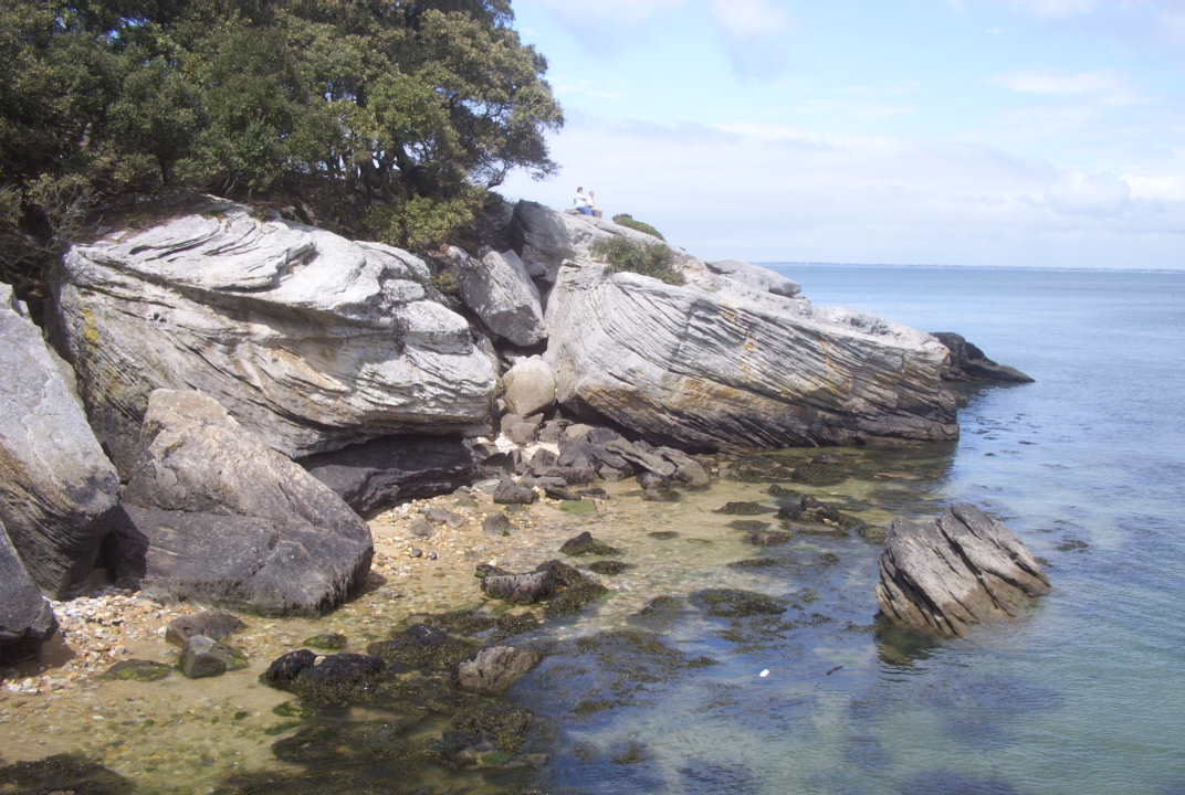 a view of rocks and water from the top of a hill