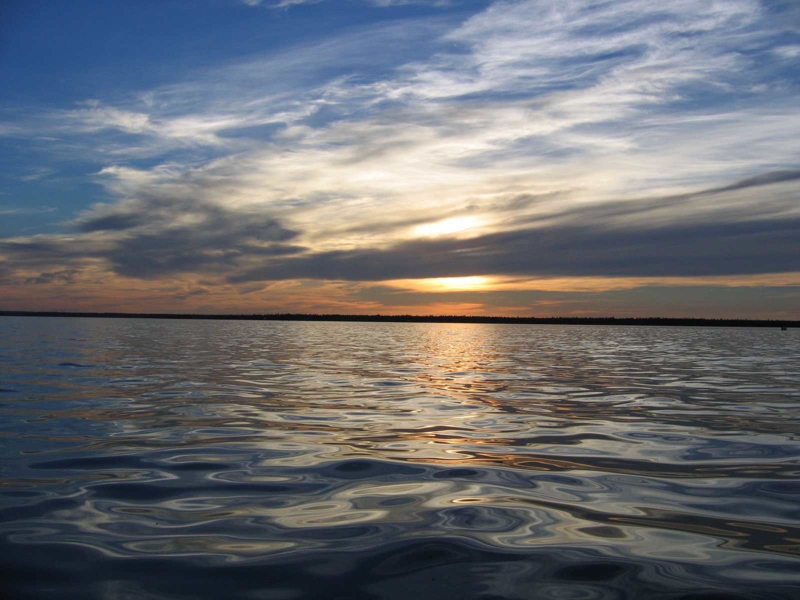 the sun shining behind clouds over a body of water