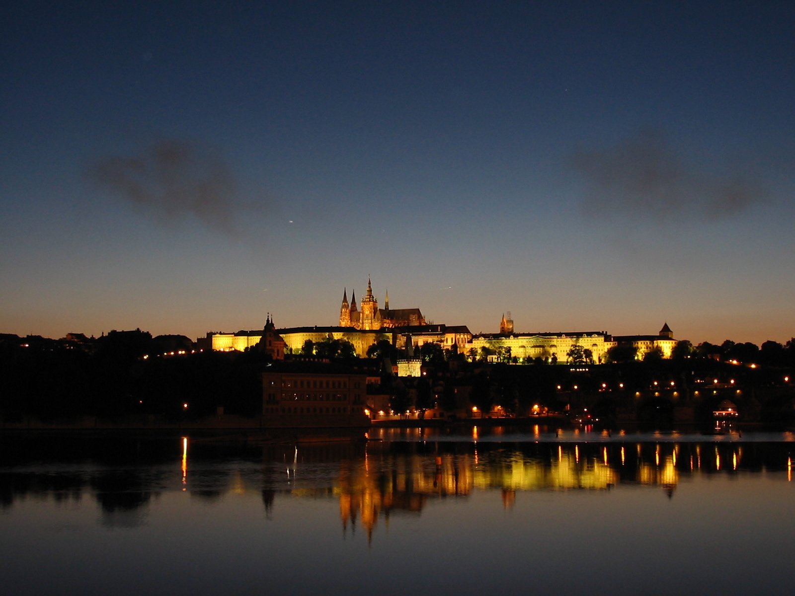 the castle of prague at night is reflected in the water