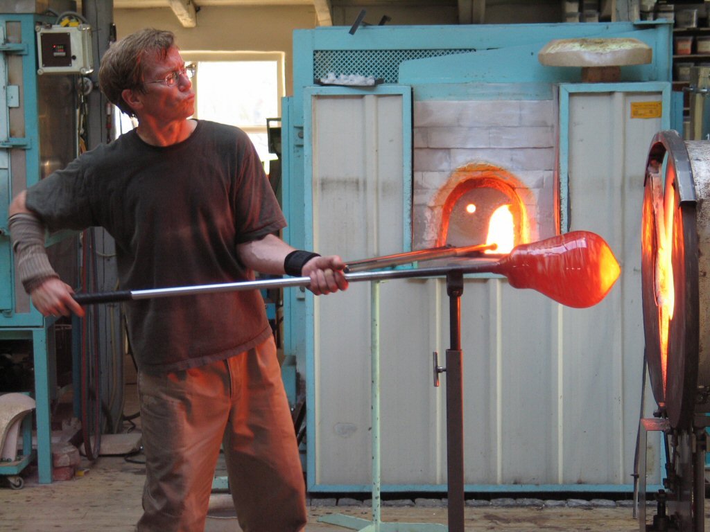 a man is throwing red glass into the shape of a boat