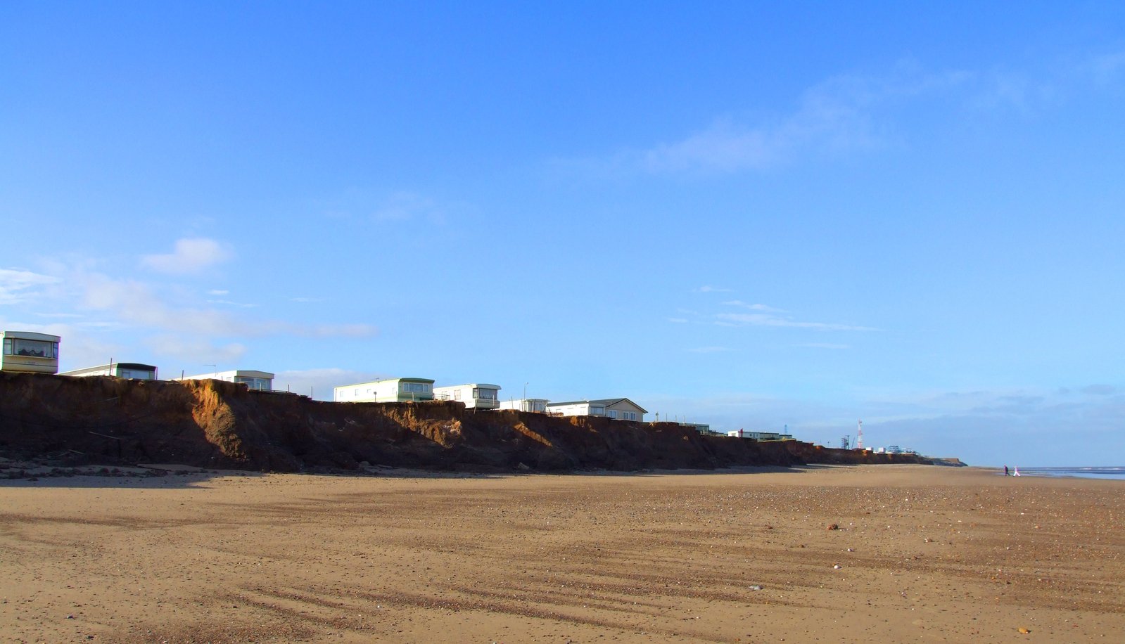 a sandy beach with houses on the hill