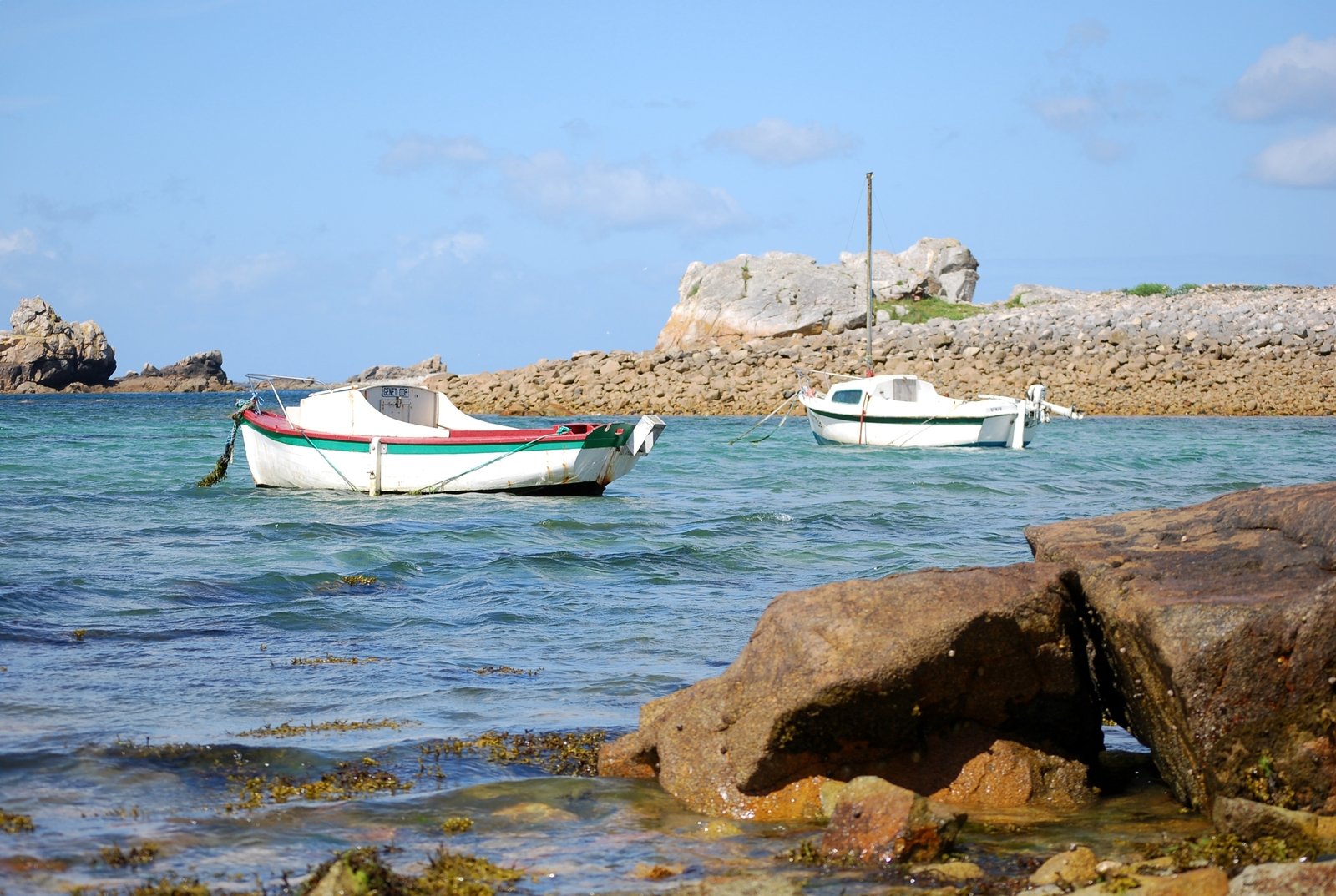 two boats on the sea with rocks in the foreground