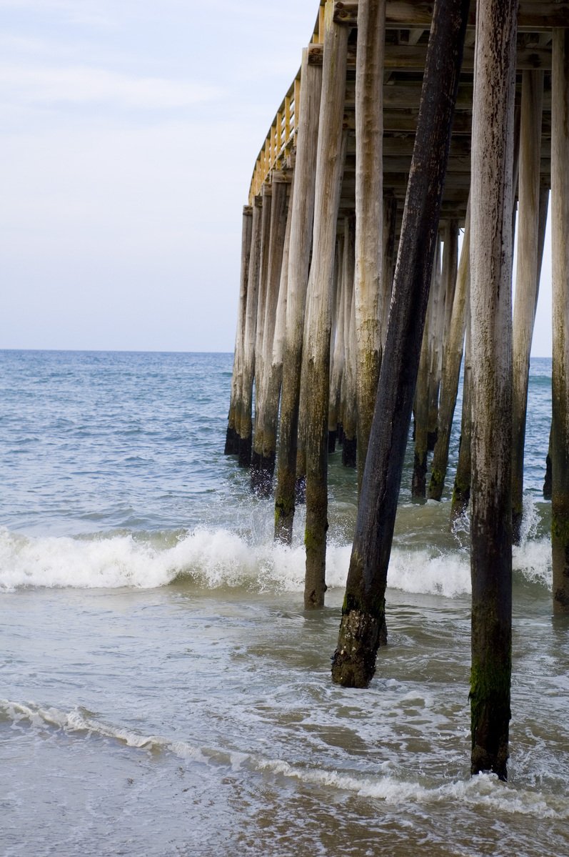 a view under the ocean with waves coming in and a pier sticking out