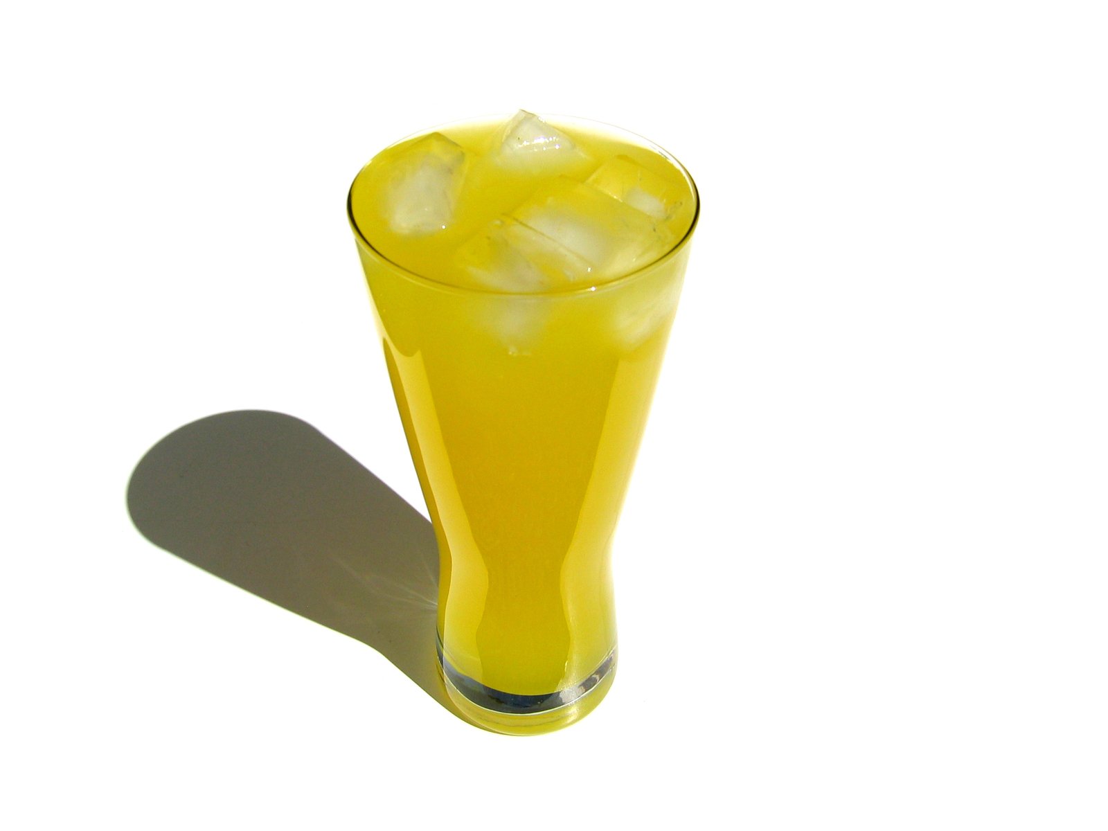 yellow drink is shown in a glass next to a white wall