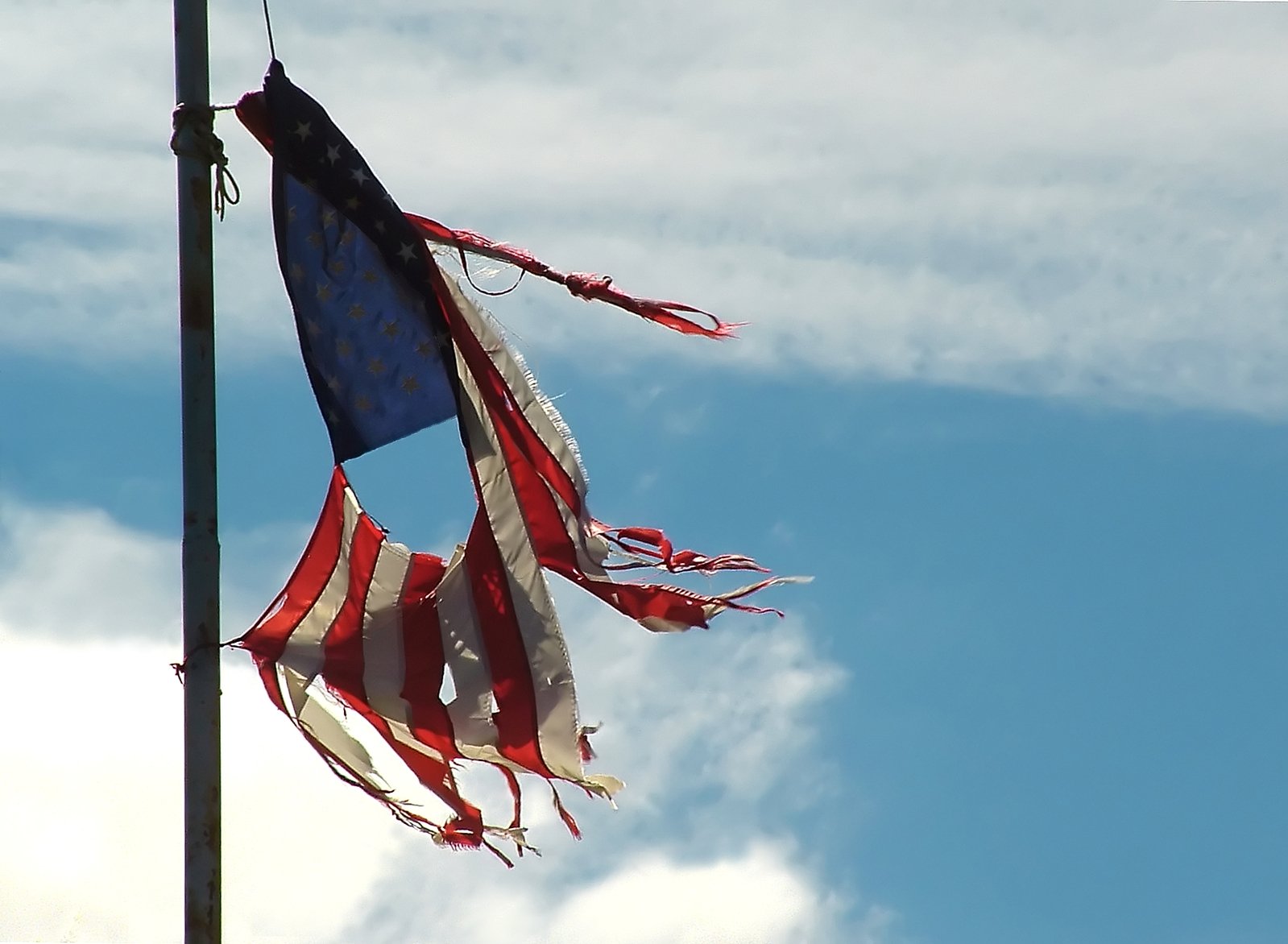 two flags are waving in the wind under a cloudy blue sky