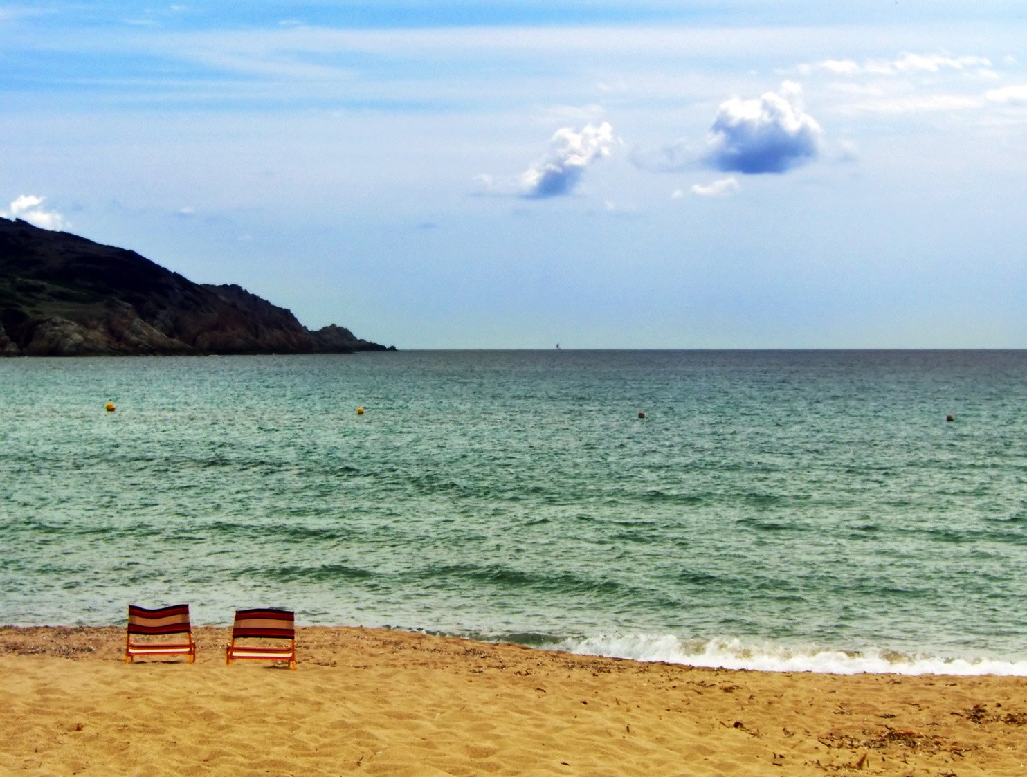 two empty chairs on the beach next to the ocean