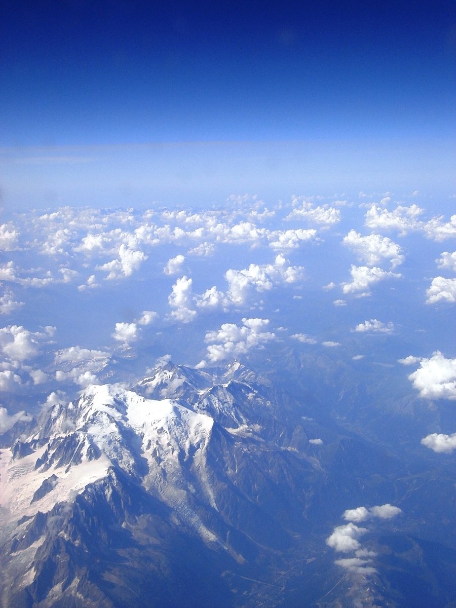 a large amount of snow covered mountains seen through an airplane window