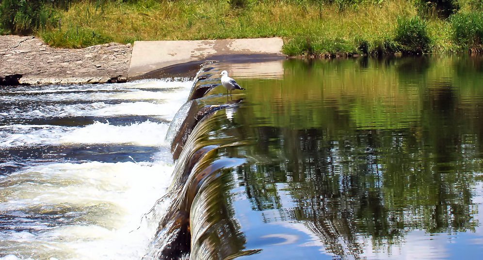 the water is rushing off a bridge into the river