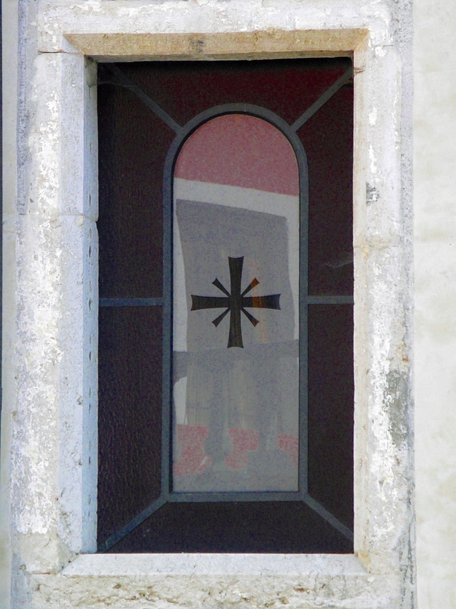 the cross is reflected in the window of a building