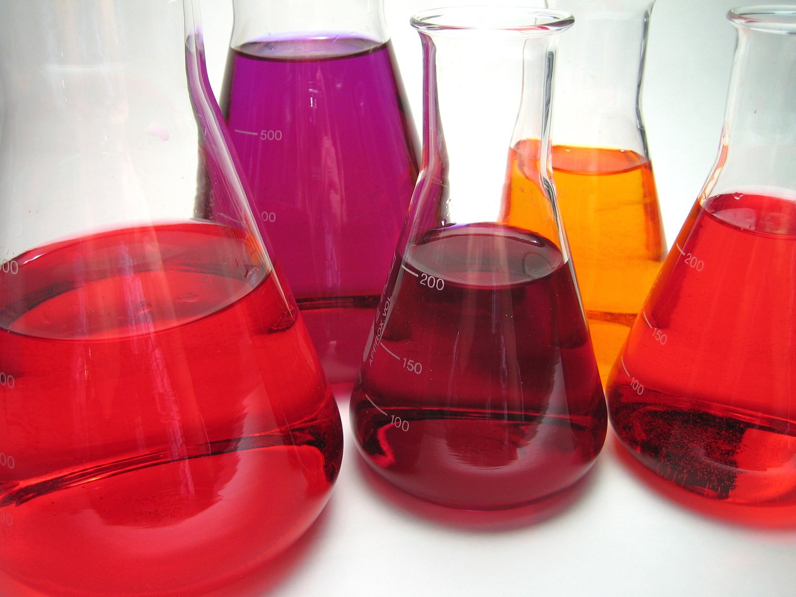 a bunch of colorful glass cups and vases that are full of liquid