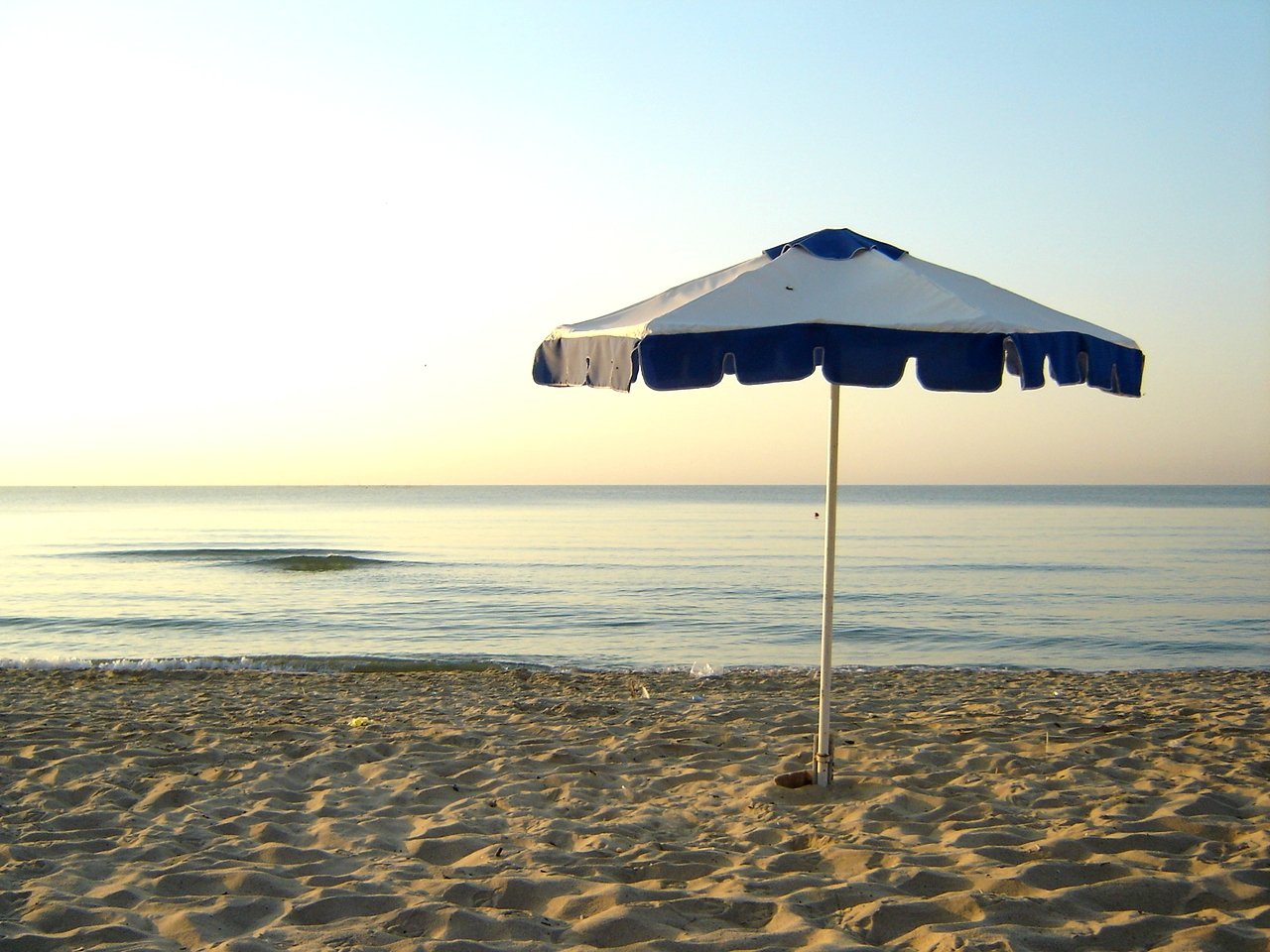 a beach umbrella sits on the sandy beach next to the ocean