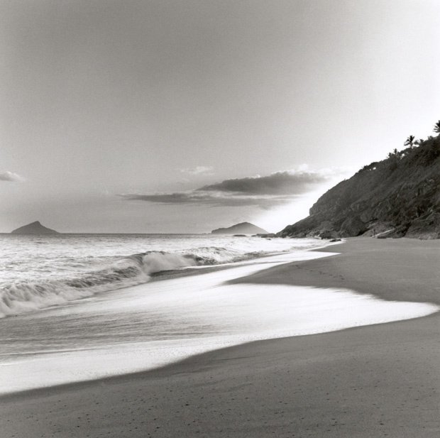 a person walking on the beach with surf on a cloudy day