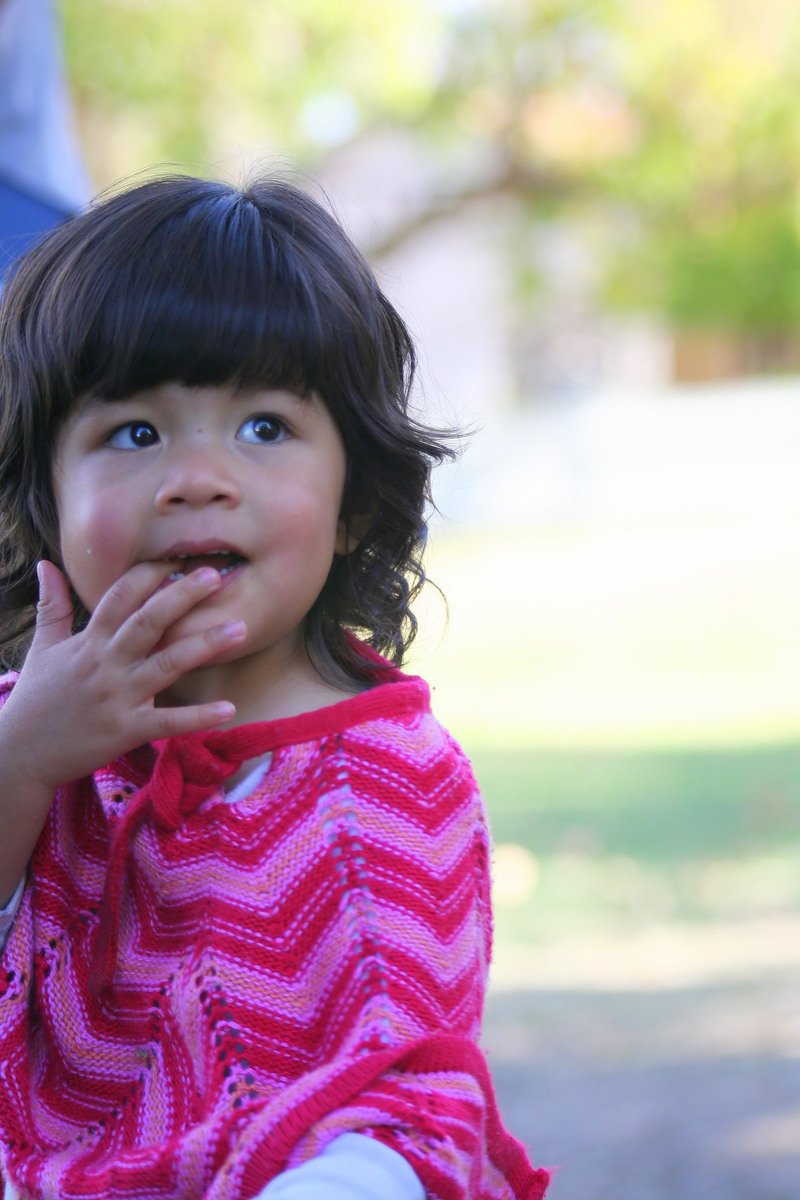 a little girl holding her hand in her mouth