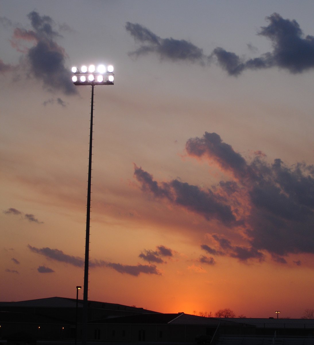 the sun is setting behind a tall pole