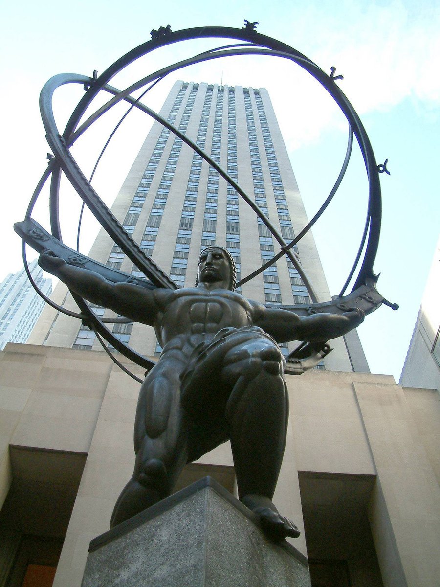 a statue in front of a very tall building