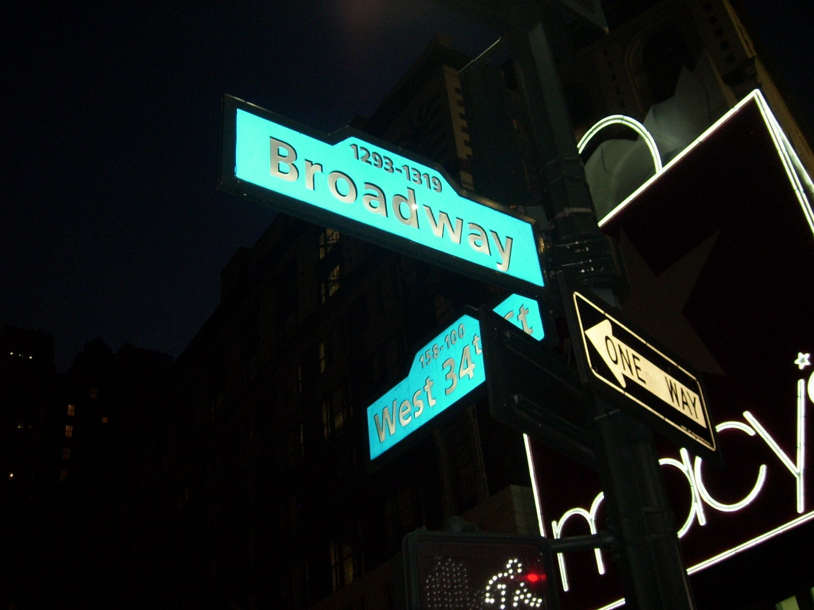 street signs are glowing green at night in front of building