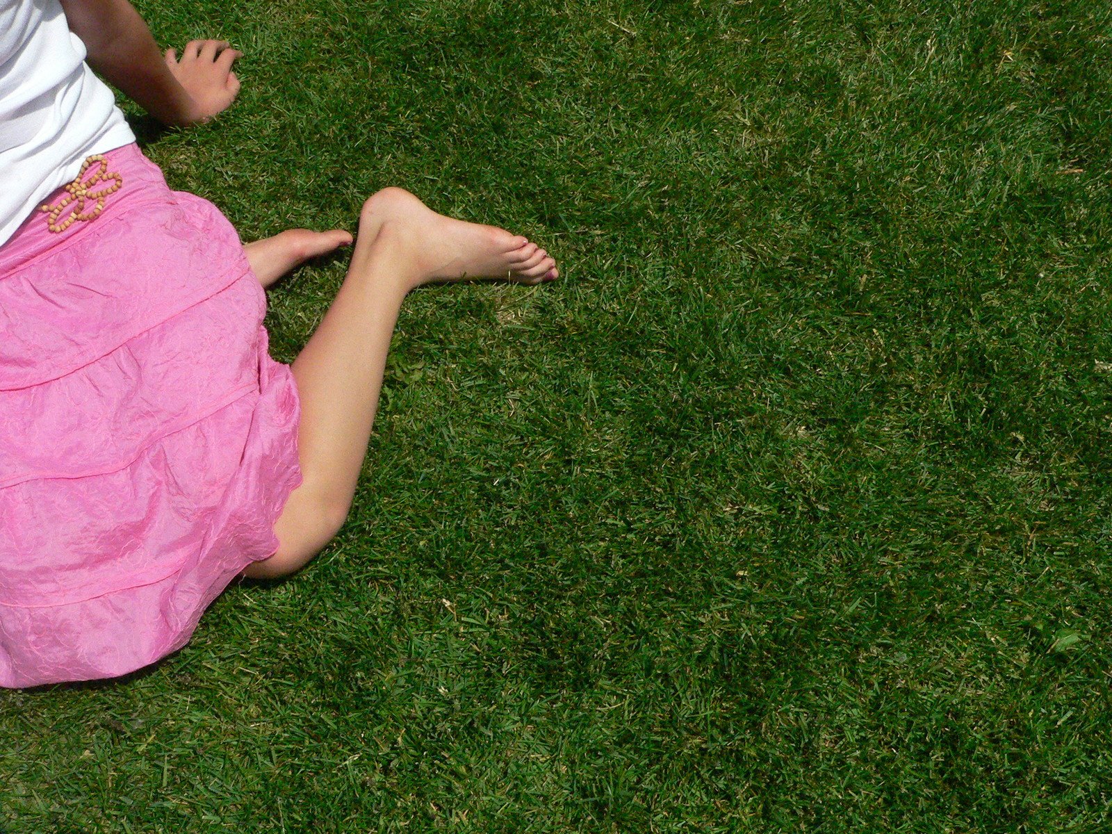 a person with pink hair sitting on the ground in grass