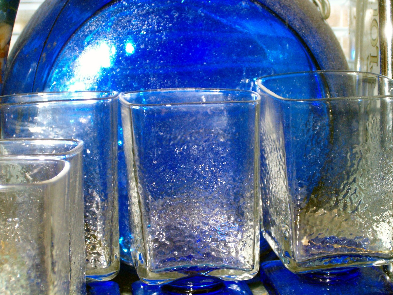 a blue pitcher is seen in front of two glasses
