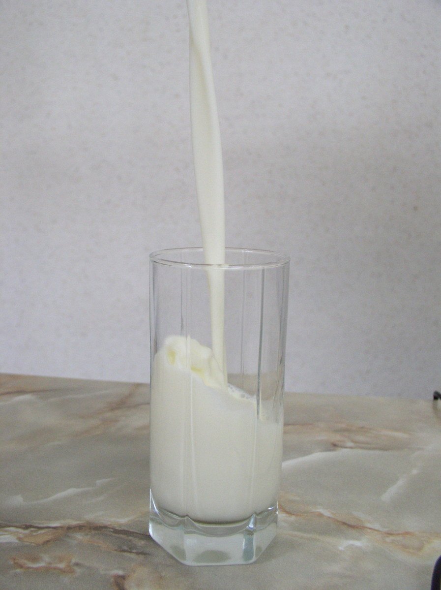 milk being poured into a clear glass on a table