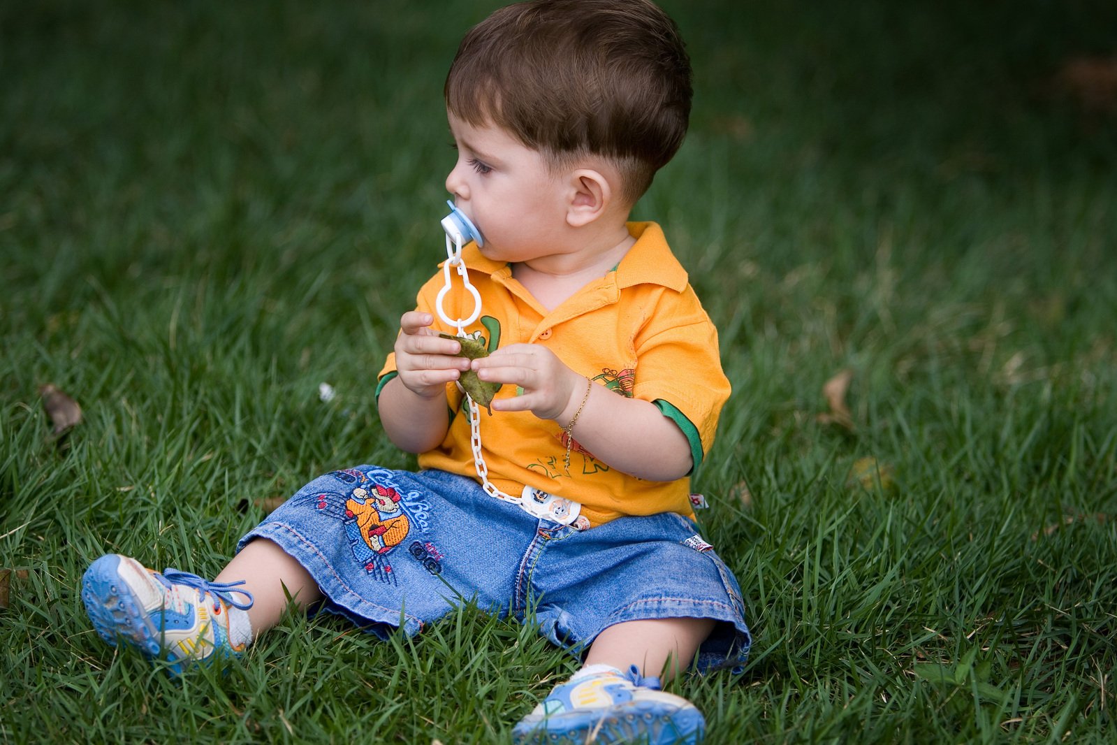 a young child sits in the grass eating soing