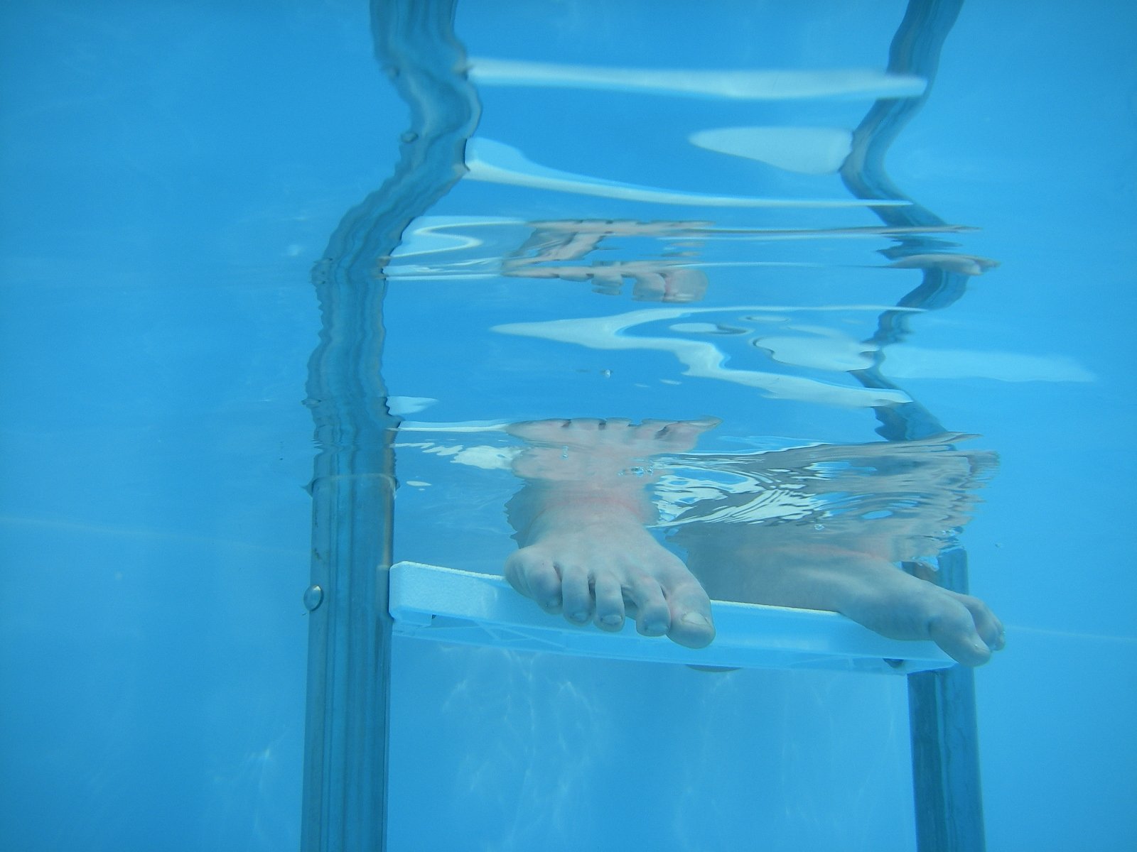 a young man floats along an edge of the pool while holding onto his board