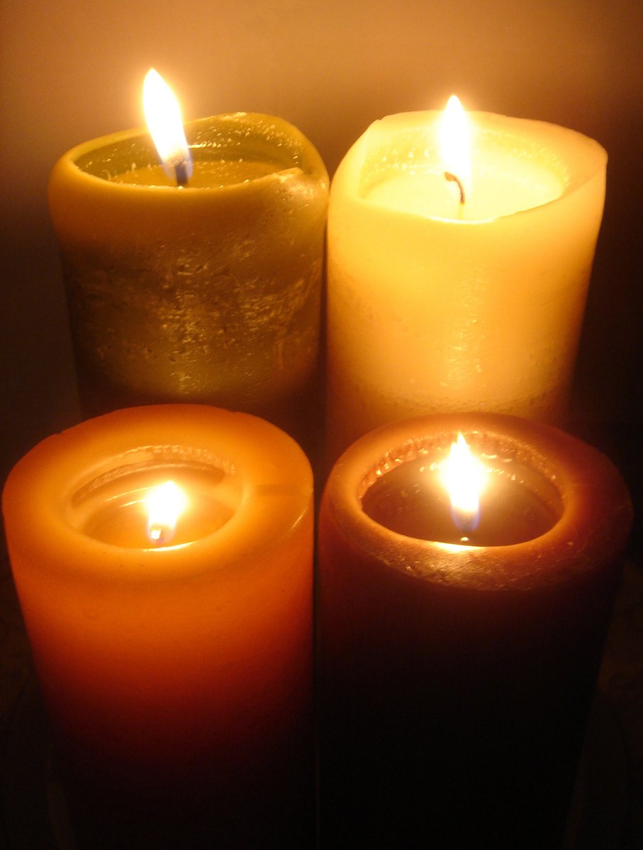 three lit candles in a row in front of a plain background