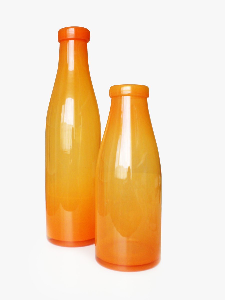 a couple of orange glass vases sitting on top of a table