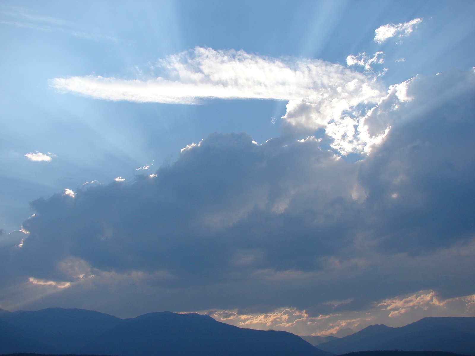 sun beams break through the clouds over the mountains