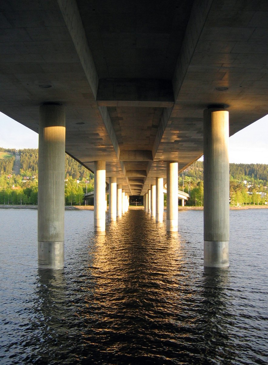 a bridge over water with two white pillars at the ends