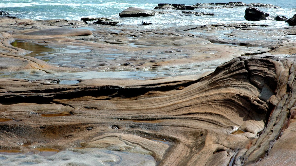 an artisticly textured beach by the ocean has very interesting layers