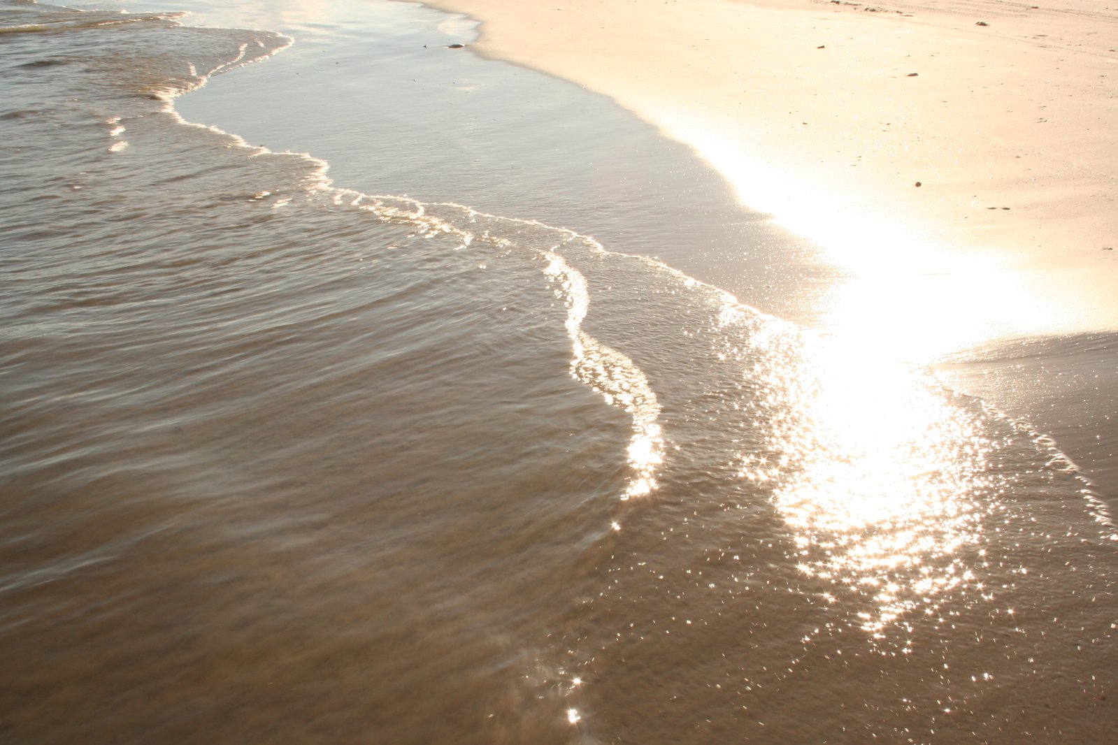 a man walking down the beach at sunset