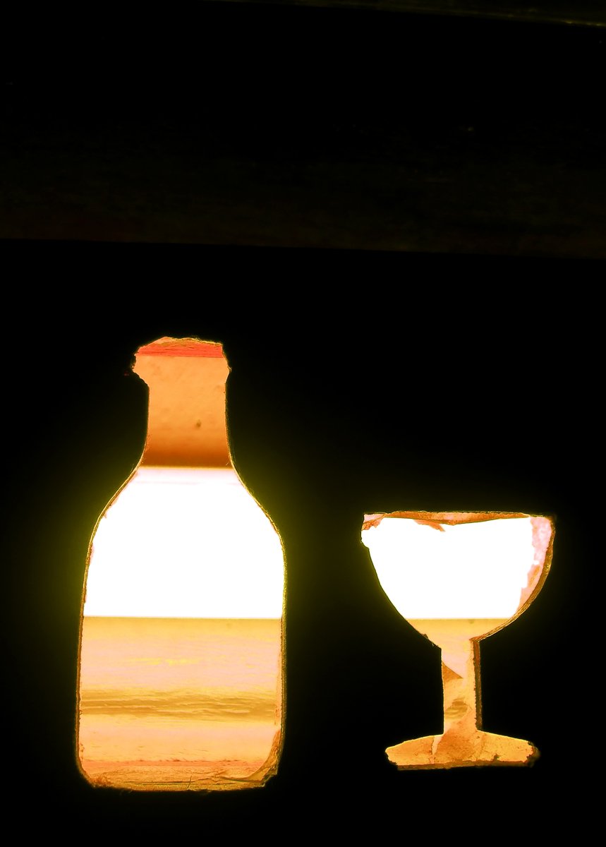 a lighted bottle in the background and a wine glass beside it