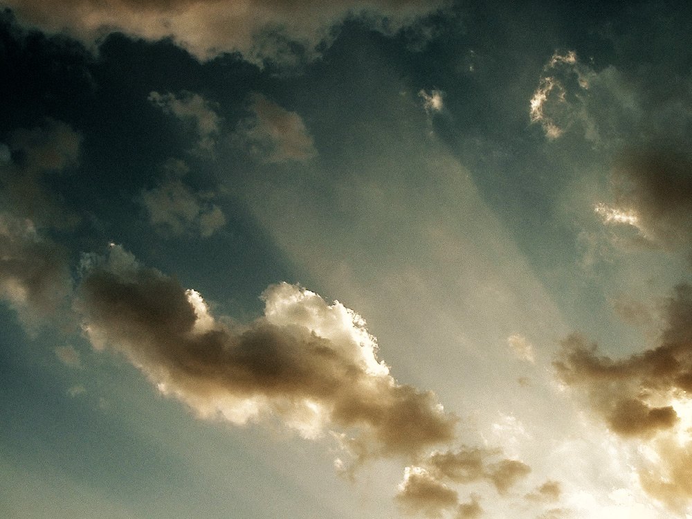 the plane flies in the distance with a lot of clouds in the sky