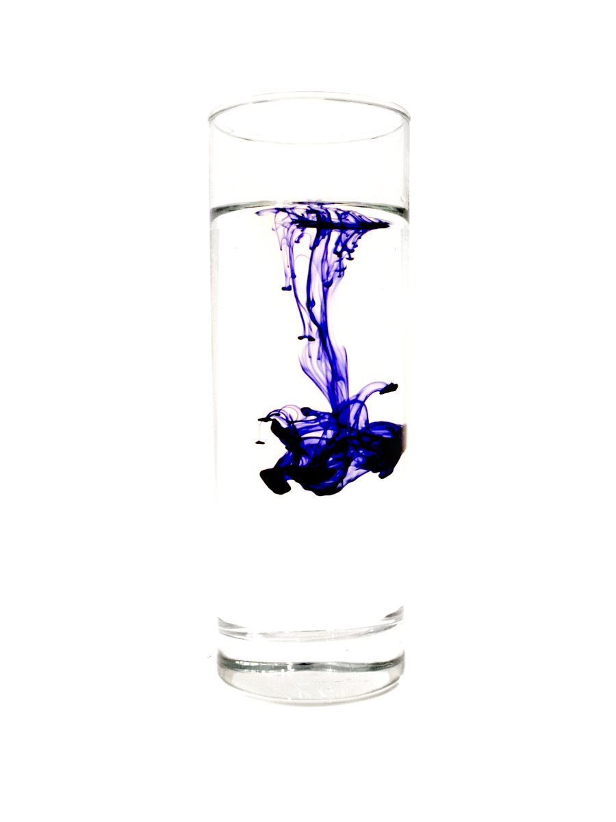 some purple and black colored paint in a glass