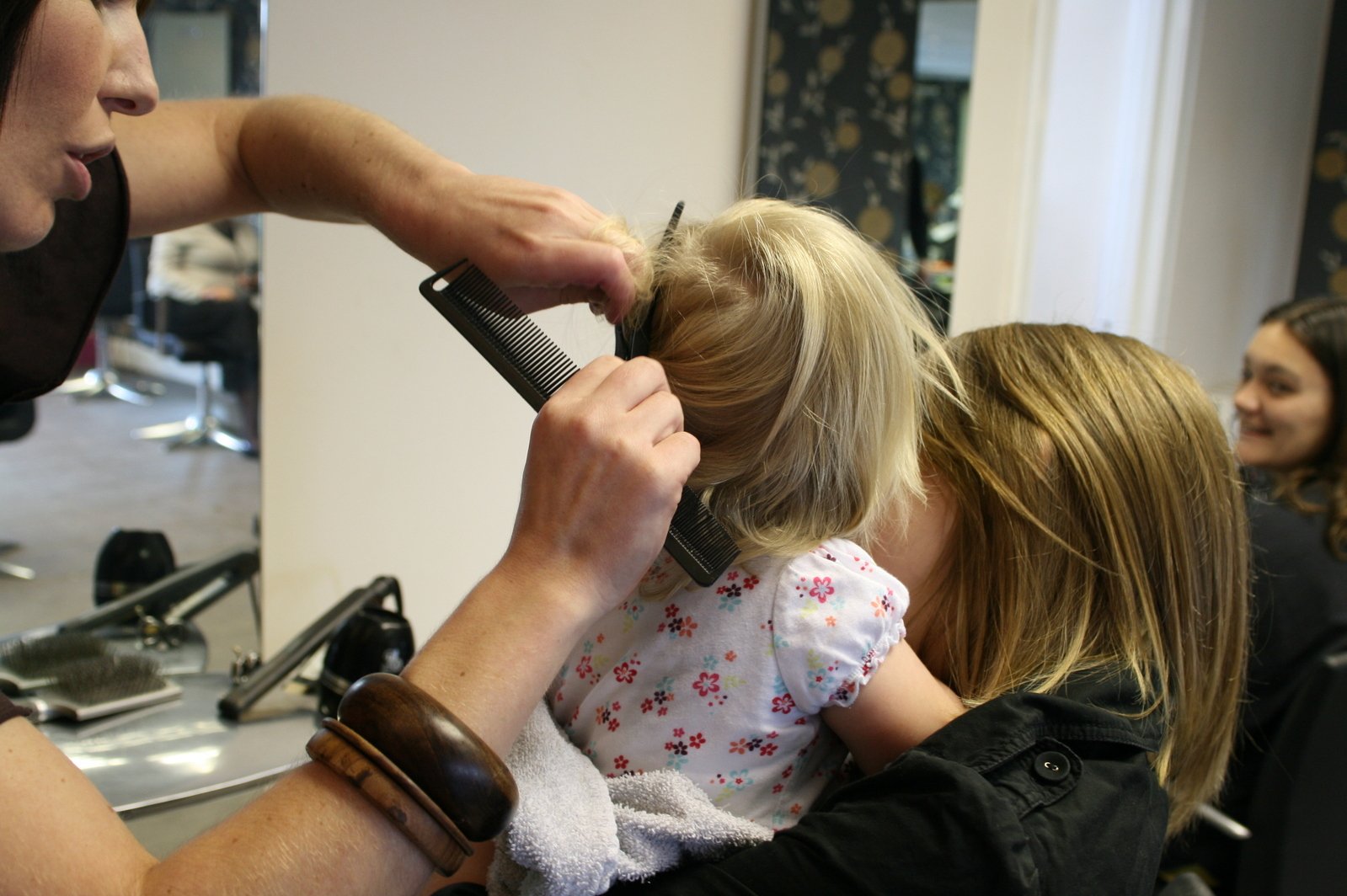 a little girl getting her hair cut by a barber