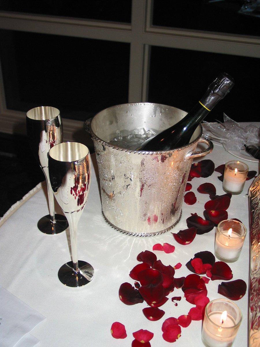 some wine and rose petals on a table