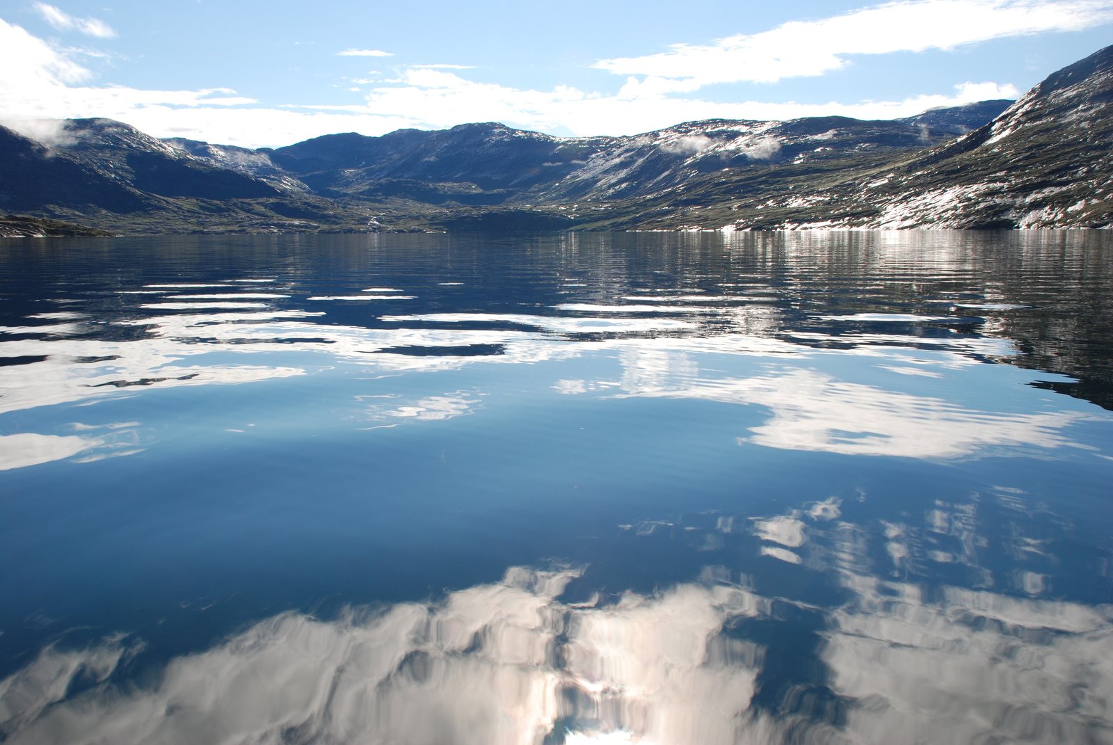 a boat on the water near mountains and trees