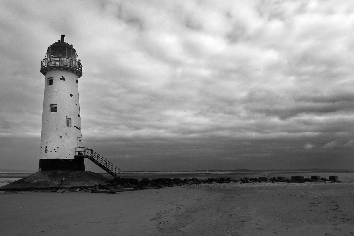 a white lighthouse sitting on top of a sandy beach