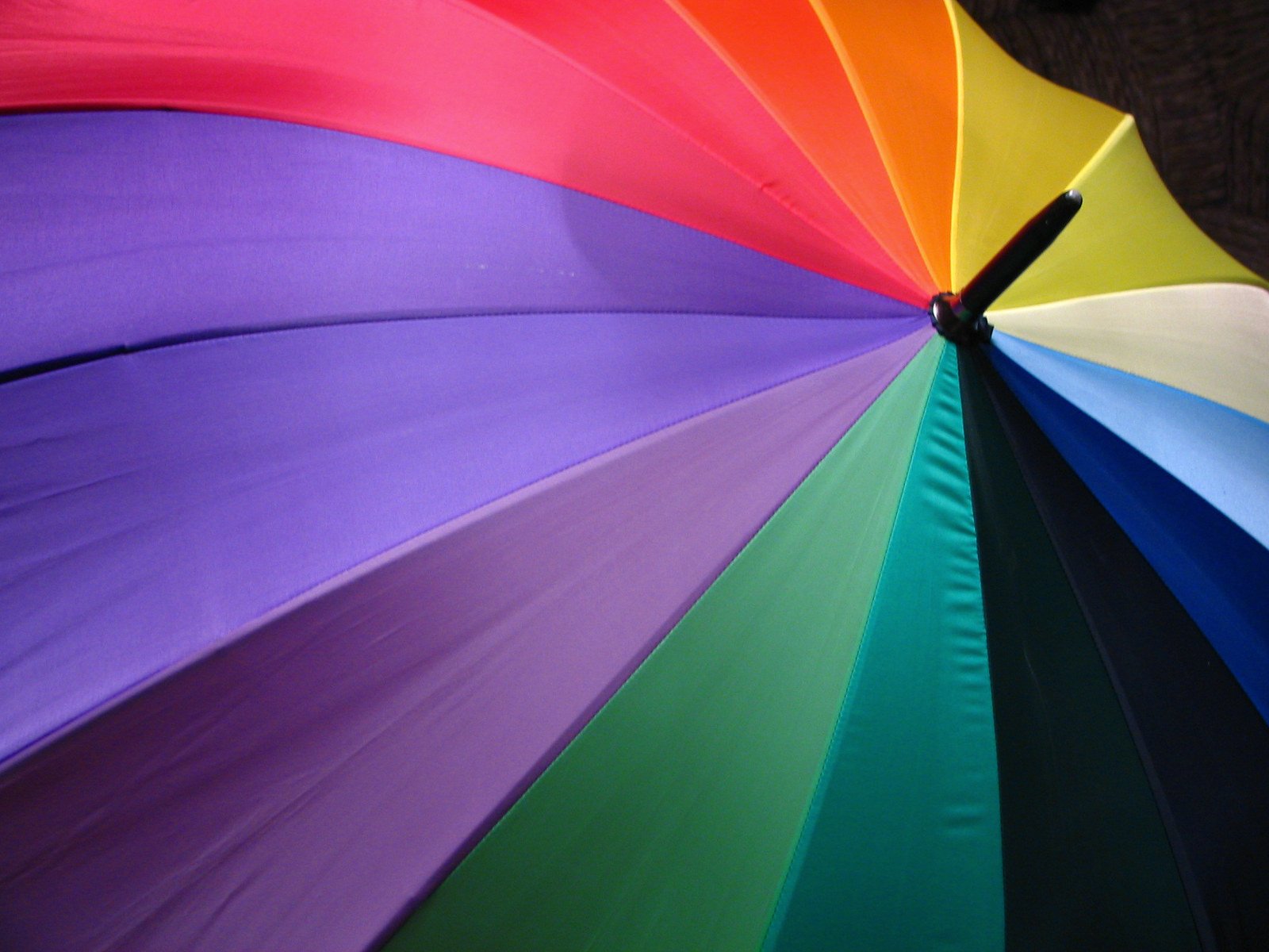 a multi - colored umbrella is opened and sitting up