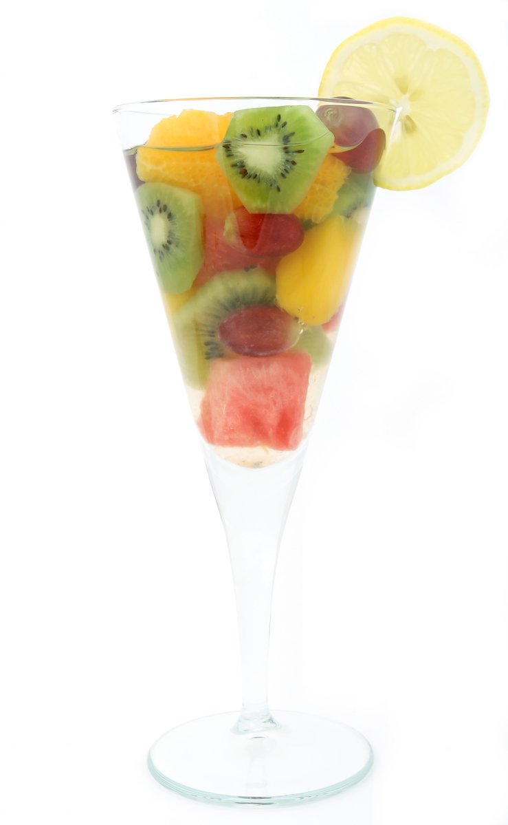 a fruit salad sitting in a glass with some sliced kiwis