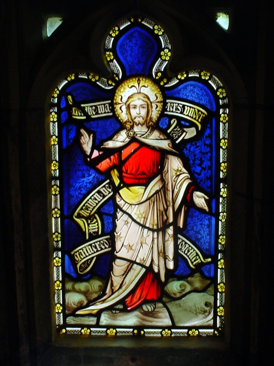 stained glass window depicting a saint standing in the wilderness