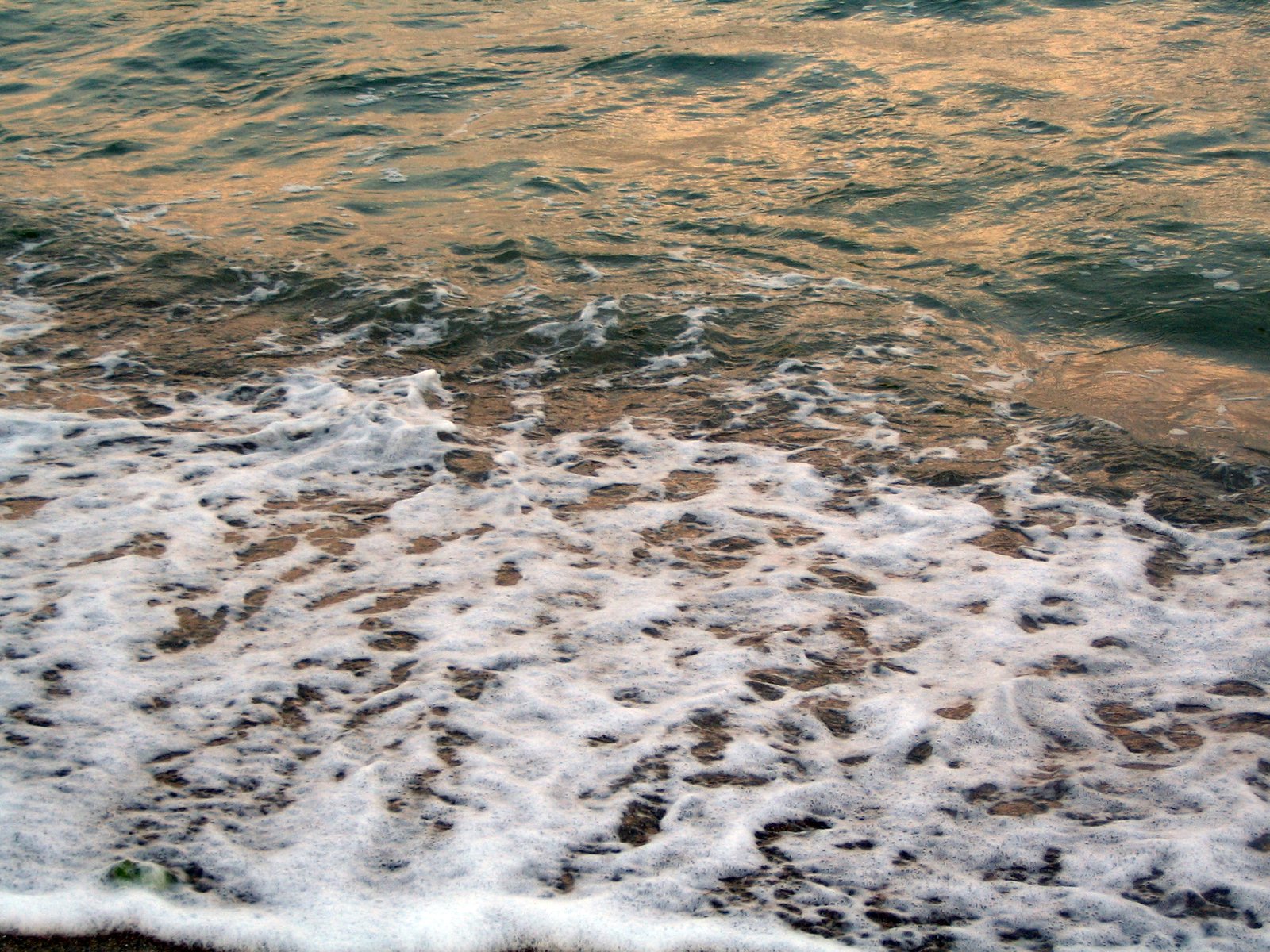 ocean waves and orange sand at sunset in the beach