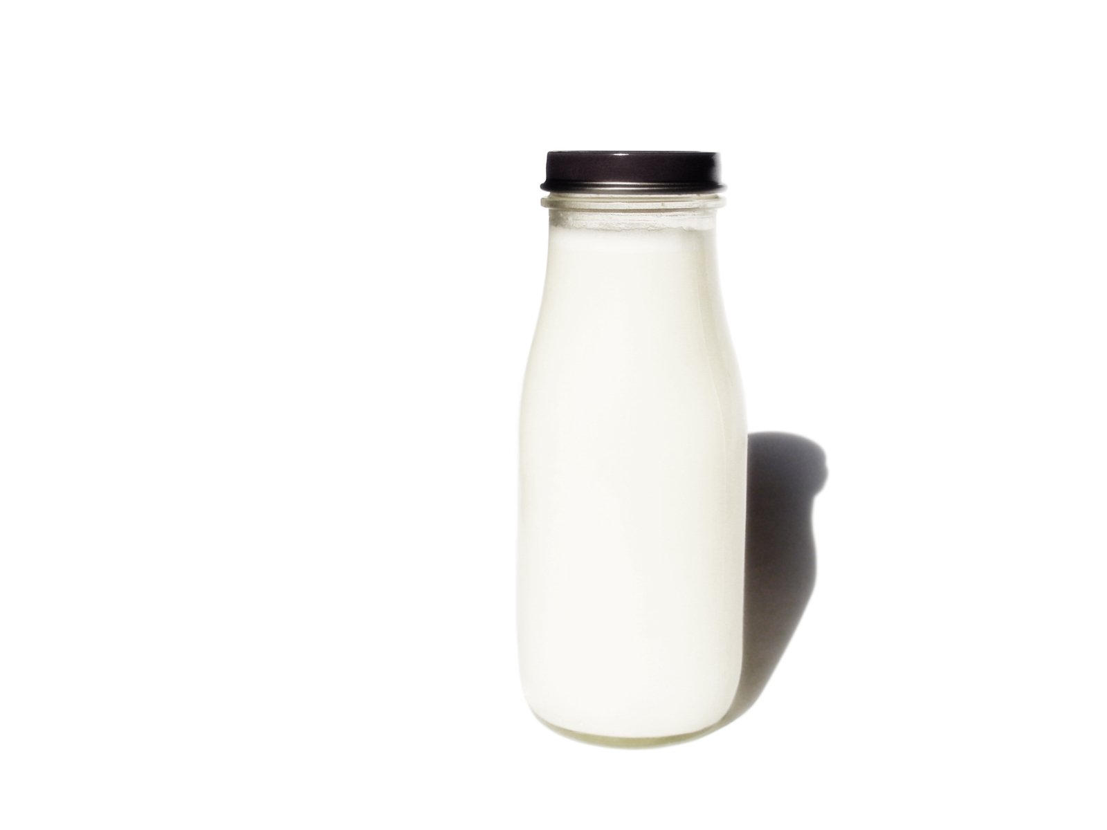 a milk bottle stands in front of a white backdrop