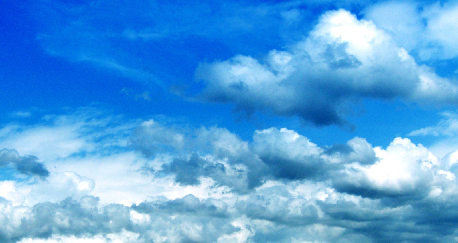 two people walking on the beach in a blue sky