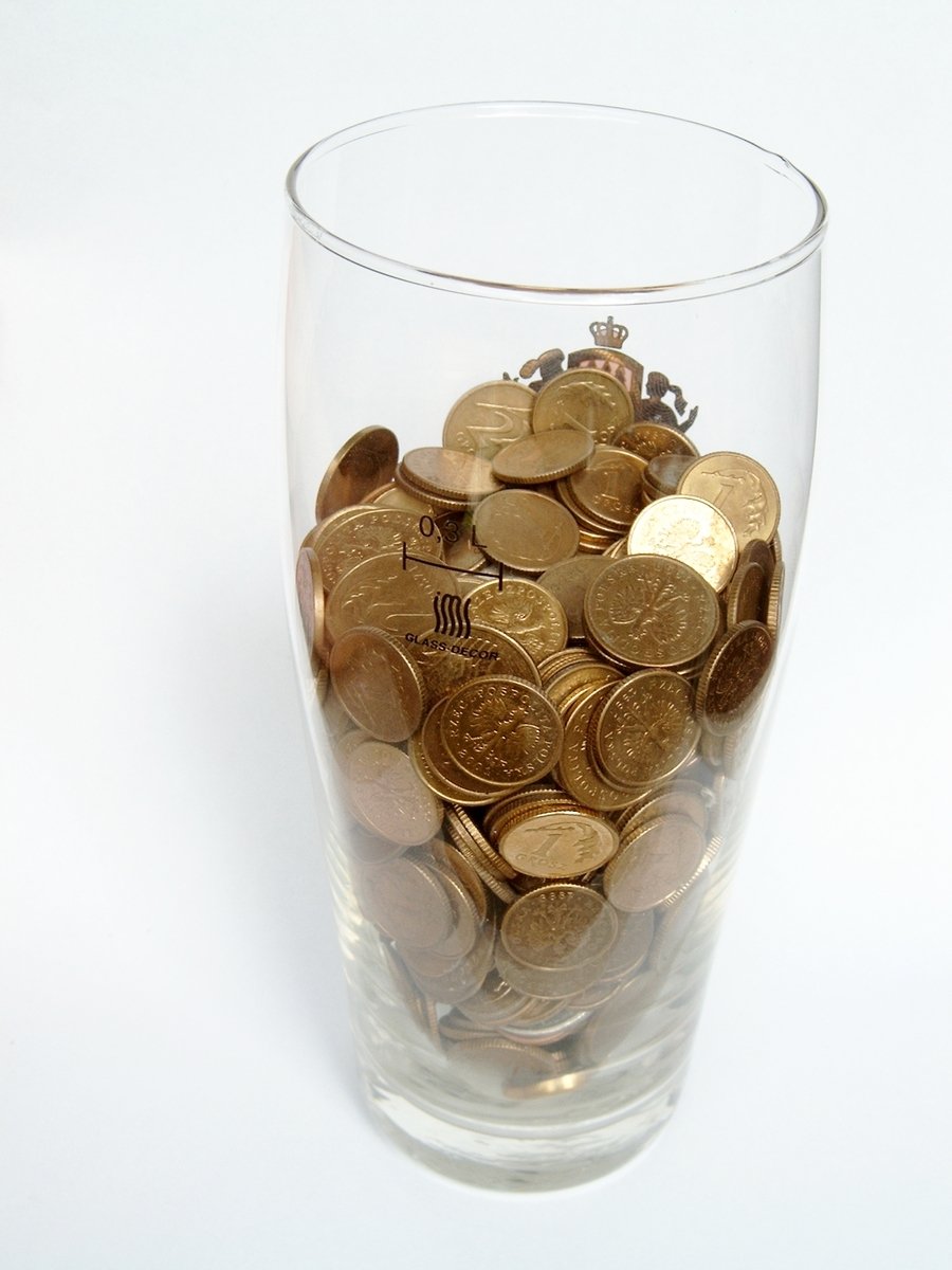a glass filled with lots of gold coins