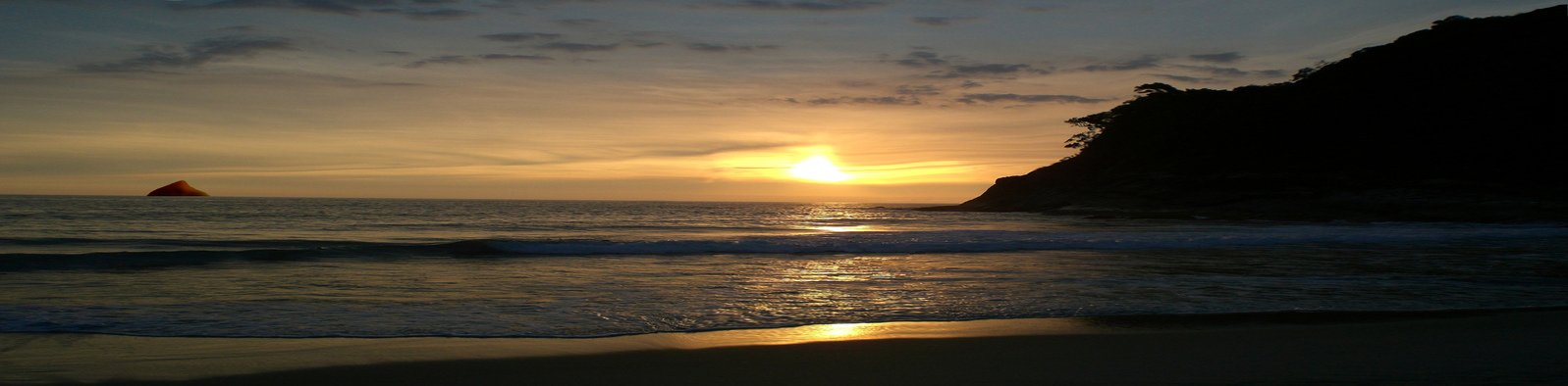 a sunset on the beach and with a few sails in the water