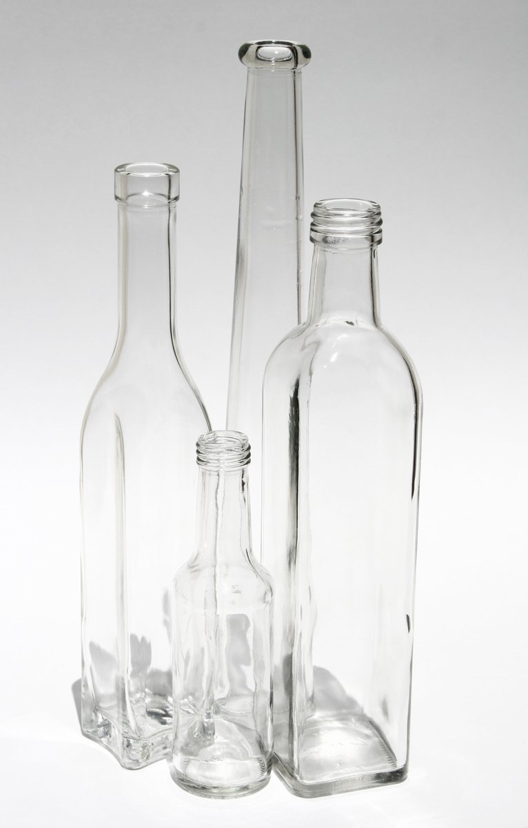 three clear bottles on a table, one empty and one empty