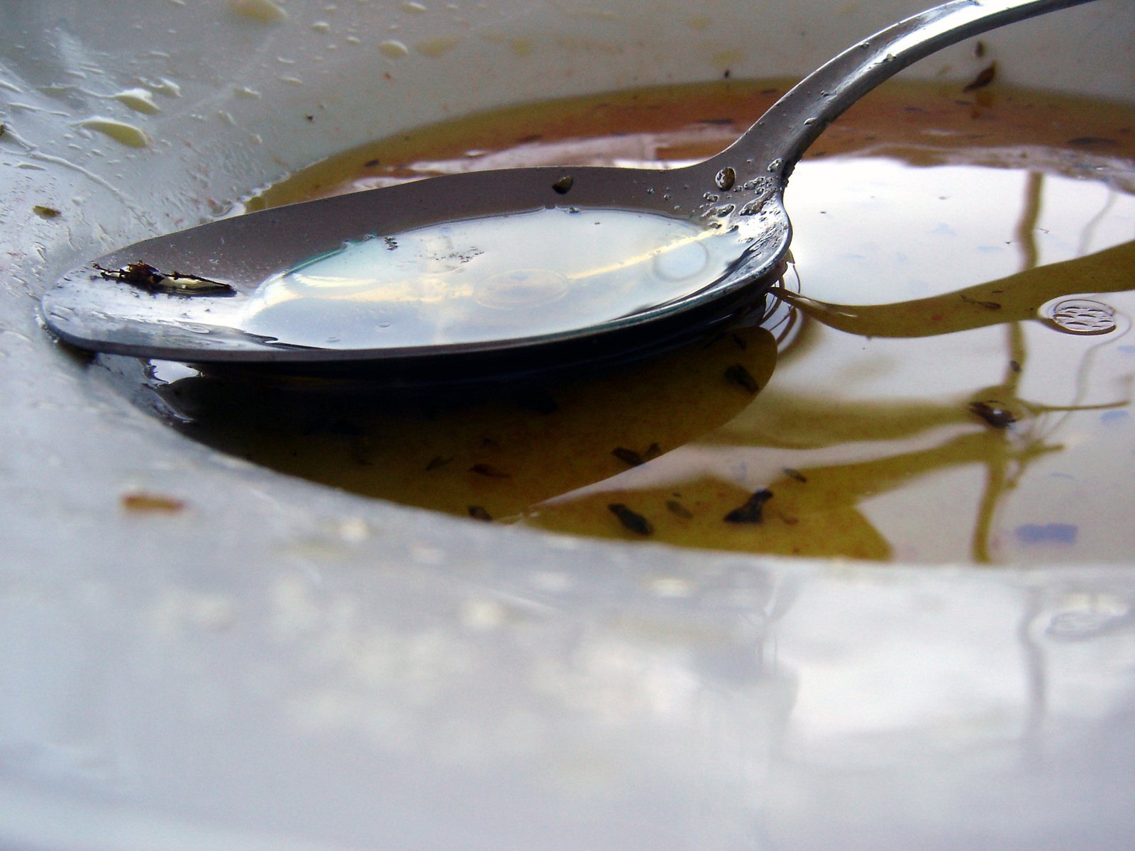 a spoon with soing in it on top of liquid