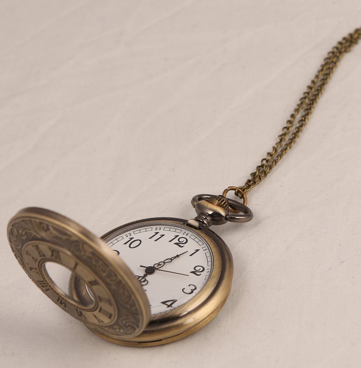 an antique pocket watch is setting on a bed